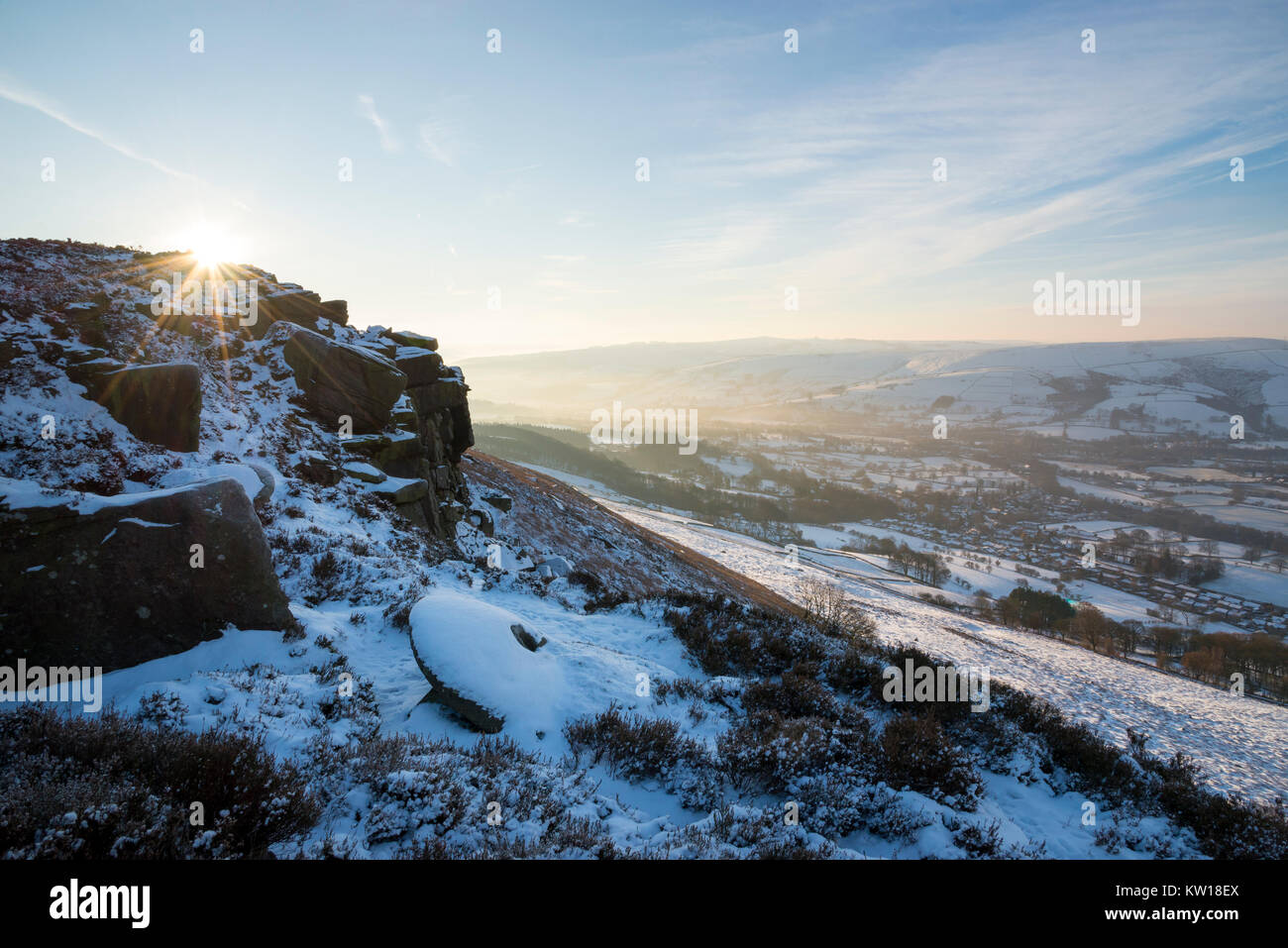 Dawn at Bamford edge in the Peak District on a cold winter morning. An old abandoned millstone covered in snow. Stock Photo