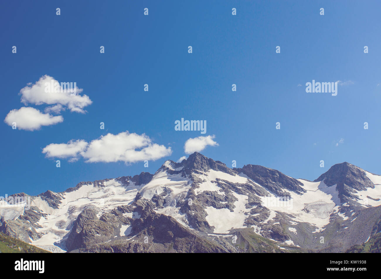 Snow capped mountain with beautiful blue sky and feathery clouds around ...