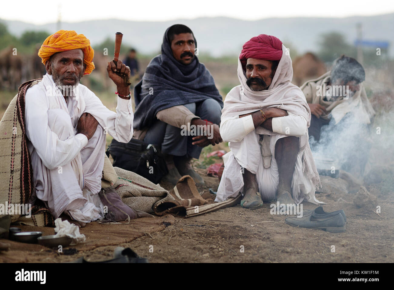 Scene at Pushkar Camel Fair, men in their morning routine bu the fireplace, smoking, Pushkar, Ajmer, Rajasthan, India Stock Photo