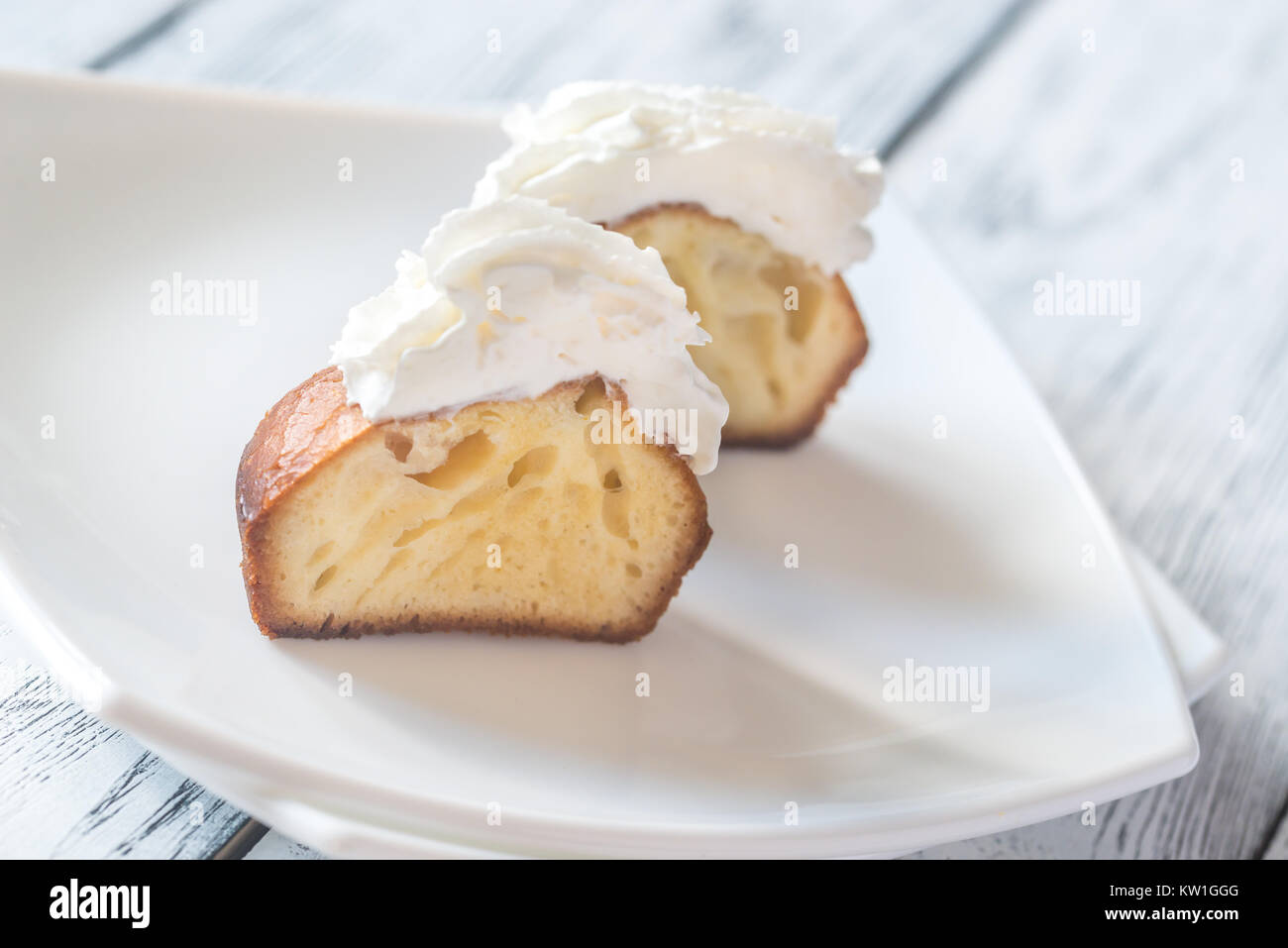 Rum baba decorated with whipped cream on the plate Stock Photo Alamy