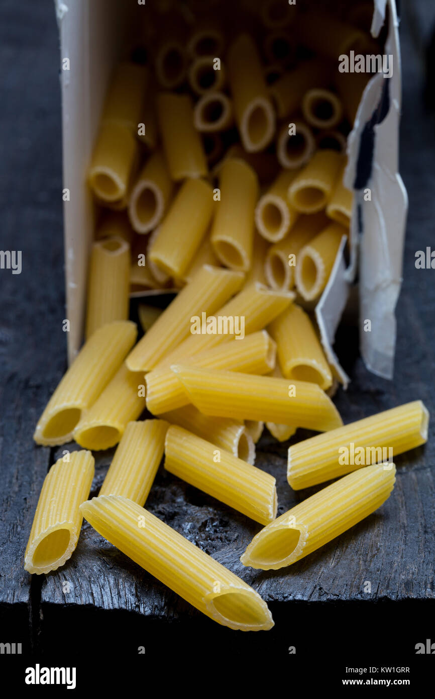 Penne noodle on dark rustic wood. Stock Photo