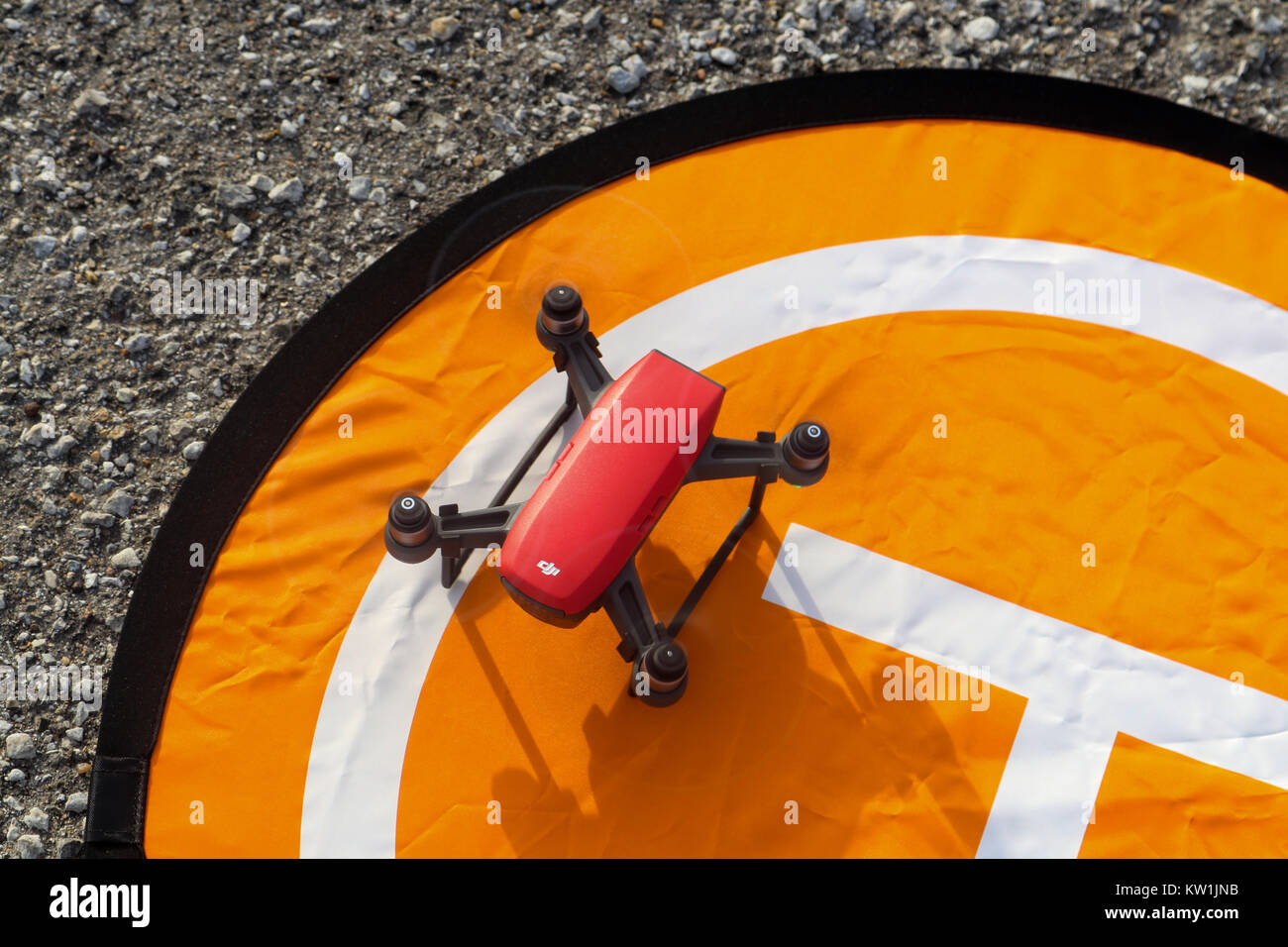 Red DJI Spark landing on an orange landing pad on gravel pavement with rotors still turning  Tulsa Oklahoma USA 12 - 28 - 2018 Stock Photo