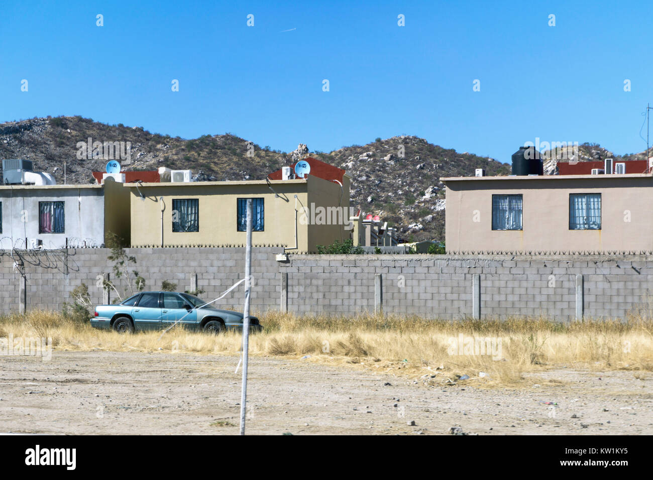 middle class housing development with individual homes all enclosed behind block wall next to Mexico state highway 15 outside Hermosillo Sonora State Stock Photo