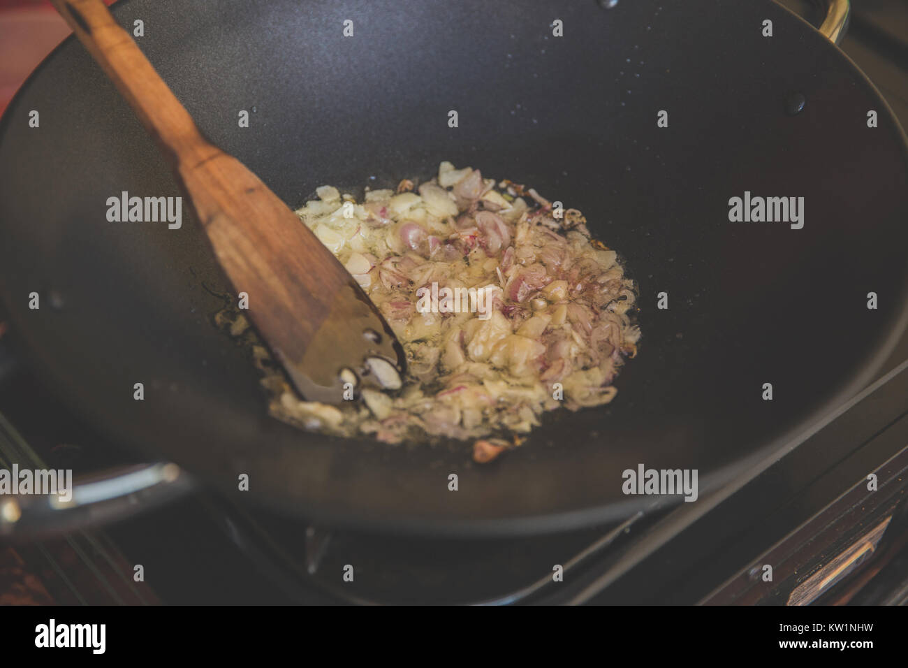 Sauteing onion and garlic on boiling oil with a ladle Stock Photo Alamy