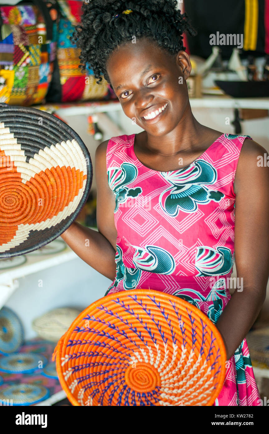 Craft stall proprietor holding decorative baskets, Handicraft Centre, Entebbe, Wakiso, Uganda Stock Photo