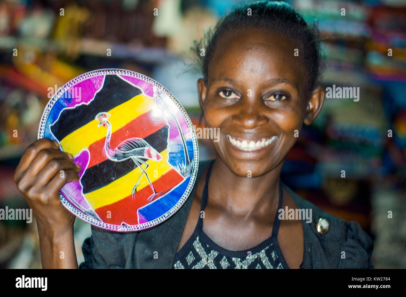 Craft stall proprietor holding hand-painted soapstone plate, Handicraft Centre, Entebbe, Wakiso, Uganda Stock Photo