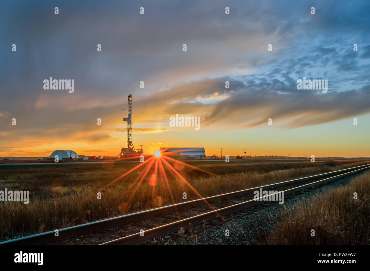 Oil rig on the field at sunset with amazing cloudy sky, near the rail ...