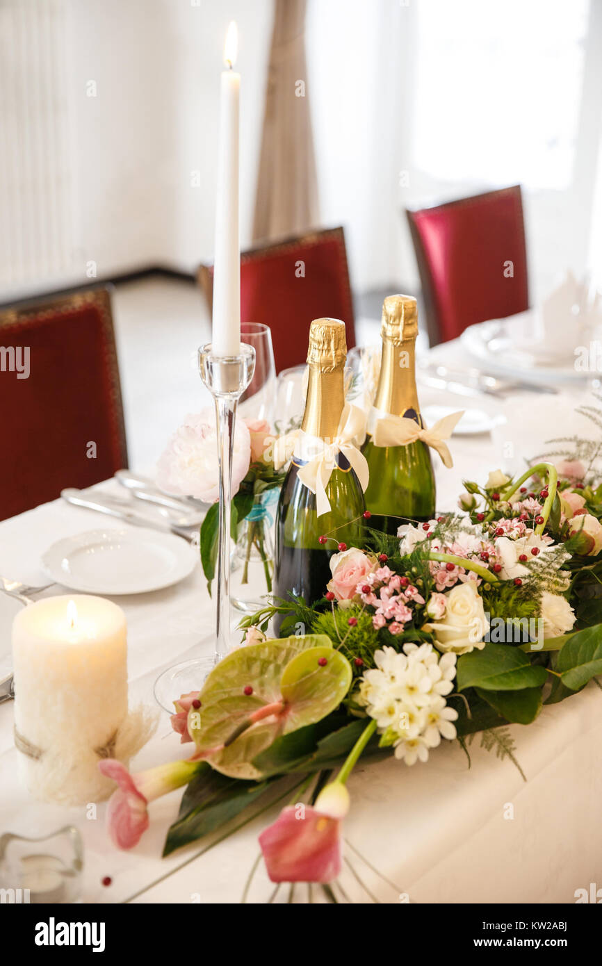 Bottles of champagne, flowers and candles on the wedding table. Stock Photo