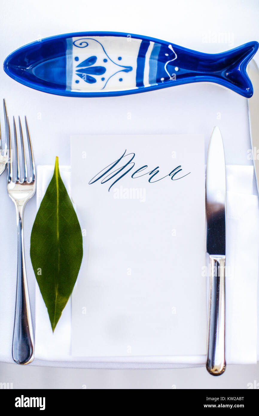 Wedding table setting with porcelain fish and green leaf. Stock Photo