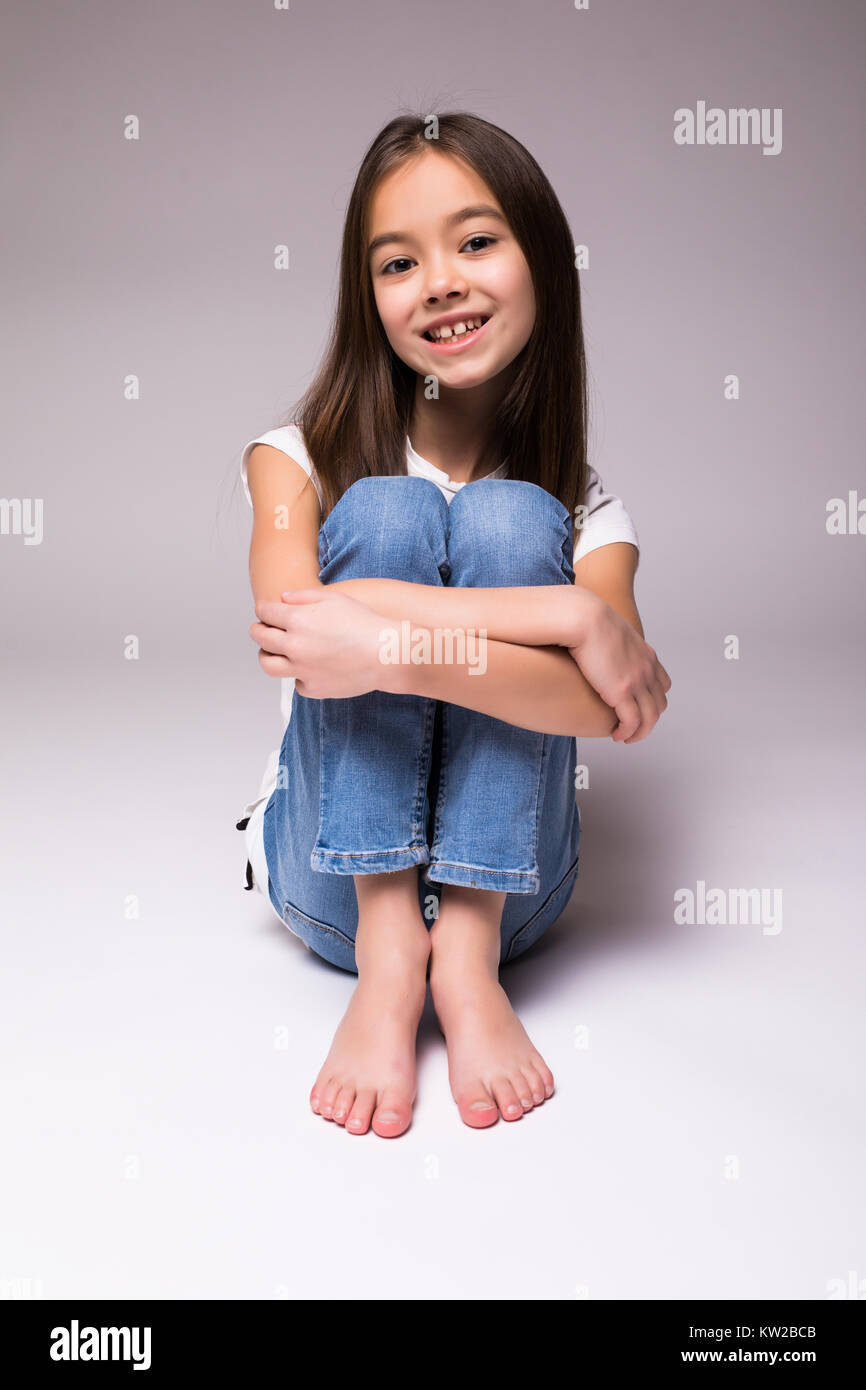 Pretty little girl sitting on the floor, Isolated over white Stock ...