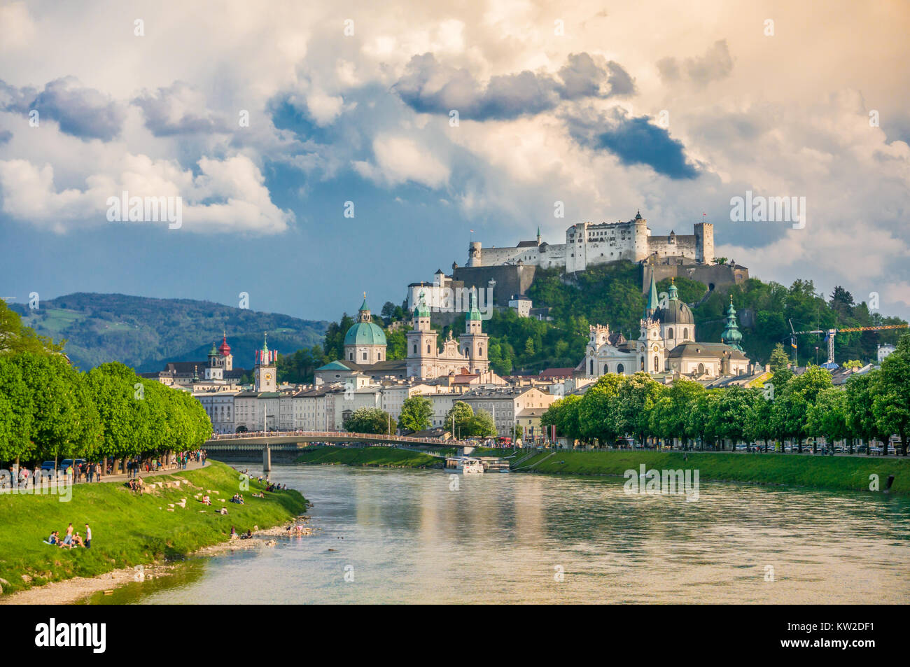 Classic view of the historic city of Salzburg with famous Festung Hohensalzburg and Salzach river in beautiful golden evening light with dramatic sky  Stock Photo