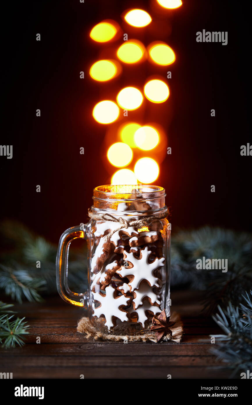 Gingerbread stars in the glass jar with golden bokeh lights at black