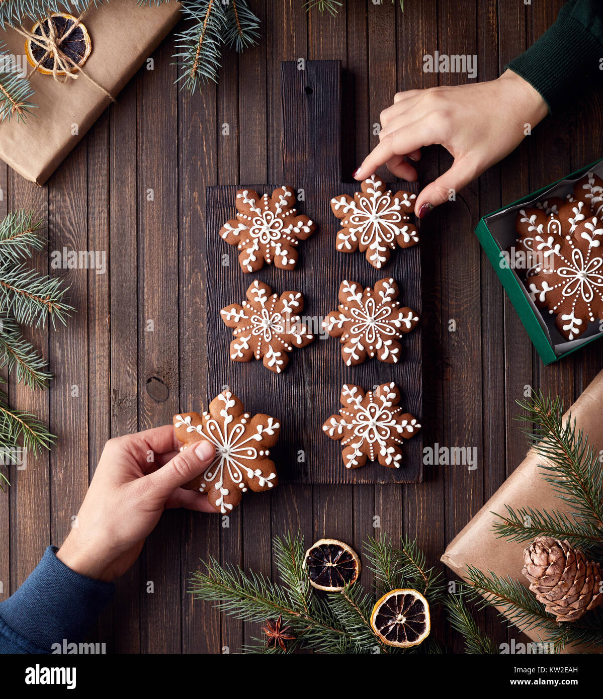 Man and woman holding Christmas gingerbread stars on rustic wooden background Stock Photo
