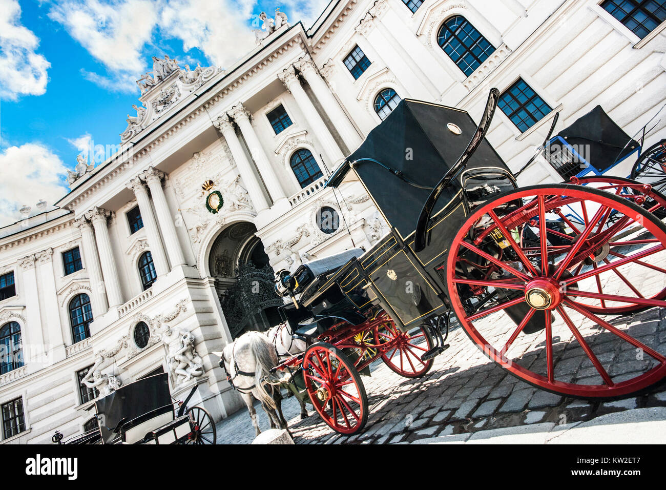 Wide-angle view of famous Hofburg Palace with traditional horse-drawn Fiaker carriages on a sunny day in Vienna, Austria Stock Photo