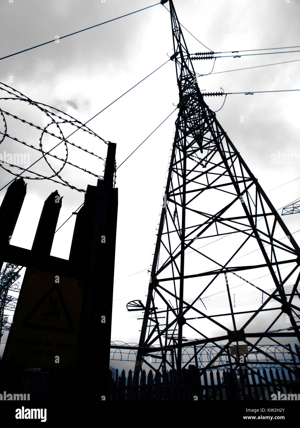 Silhouette of electricity pylon and security fence Stock Photo