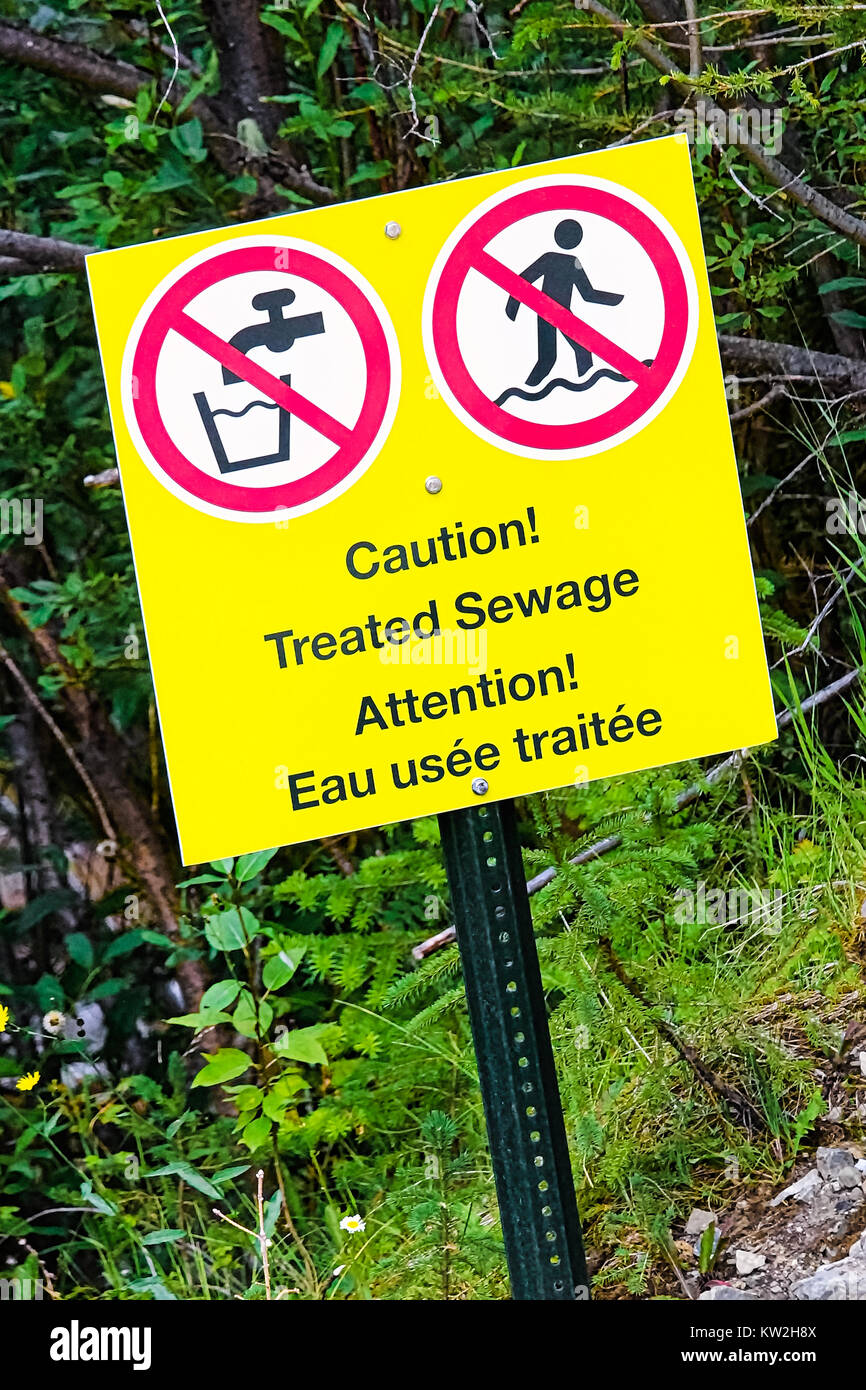 A caution treated sewage warning near running water. Stock Photo