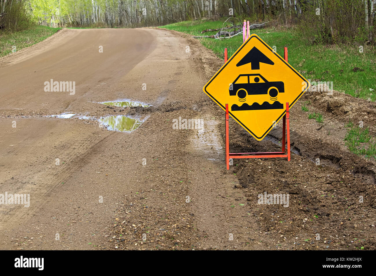 A bumpy road ahead sign with a large pothole. Stock Photo