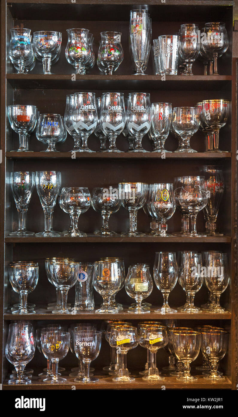 Assortment of beer glasses of different Belgian beers displayed on wooden shelves in café, Belgium Stock Photo