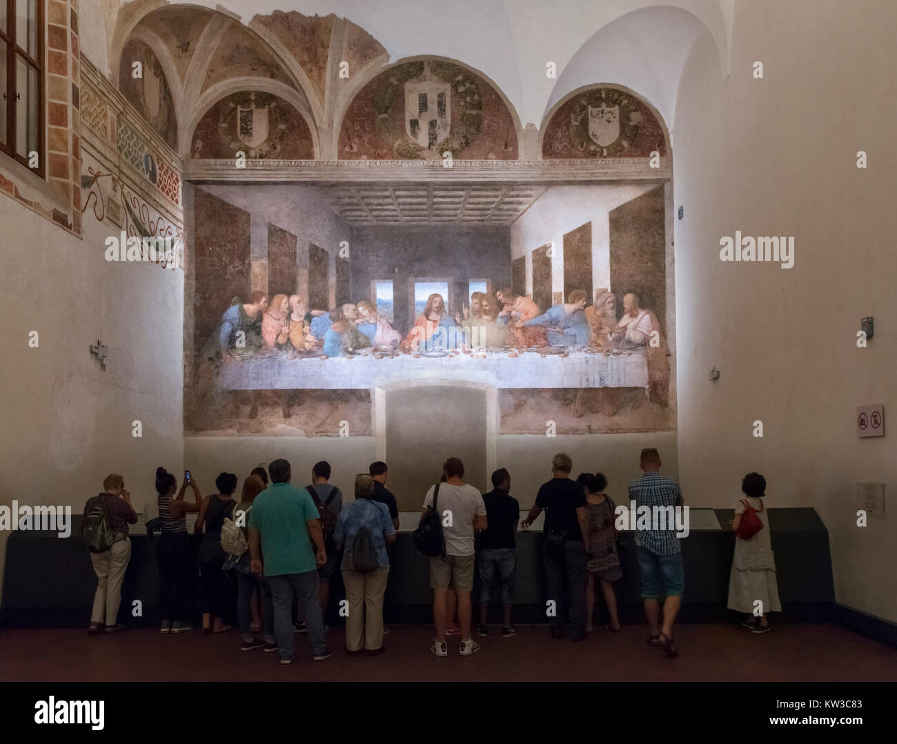 Visitors in front of The Last Supper (Cenacolo Vinciano) by Leonardo da Vinci (1452-1519) c.1494-98, a fresco in the refectory of the Monastery of Santa Maria delle Grazie, Milan, Italy Stock Photo