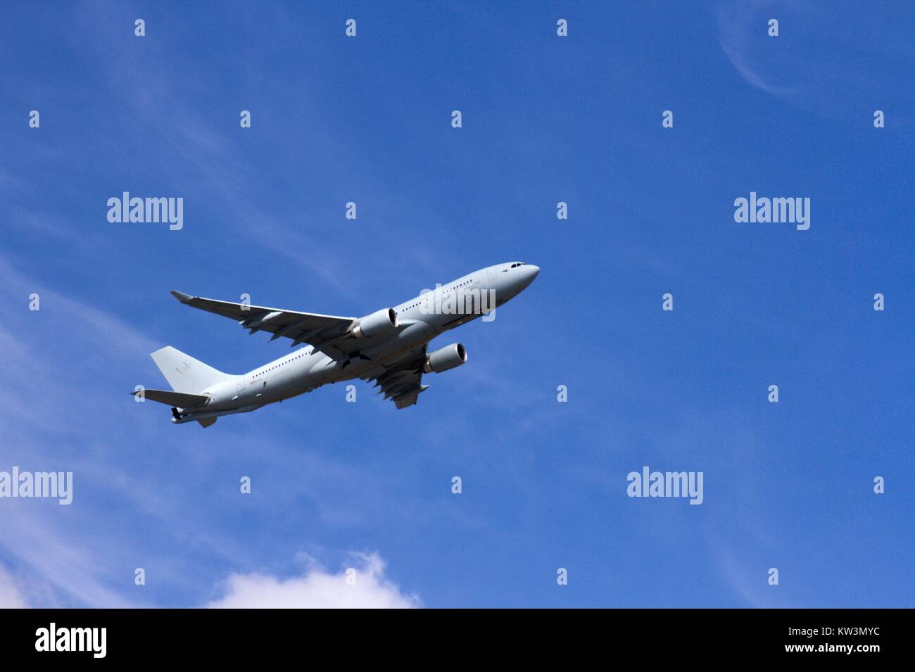 Jumbo jet plane flying upwards against a bright blue sky. Stock Photo