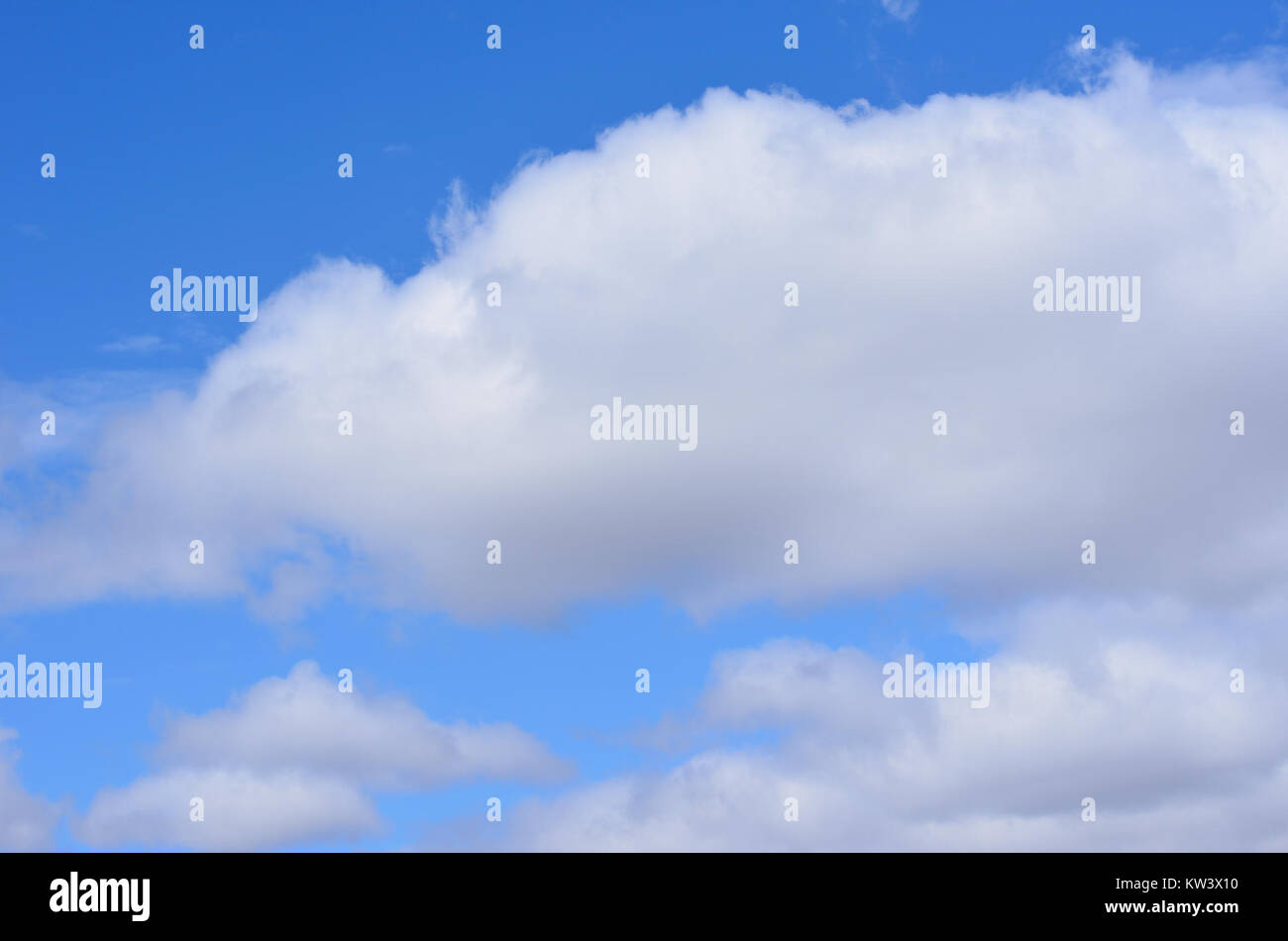 A serene landscape featuring a clear blue sky and fluffy white clouds ...