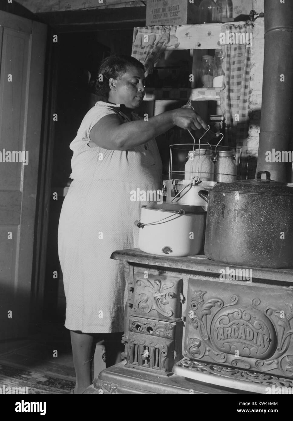 A woman stands in a kitchen using a pressure cooker to can corn in Saint Mary's County, Maryland, September, 1940. Stock Photo