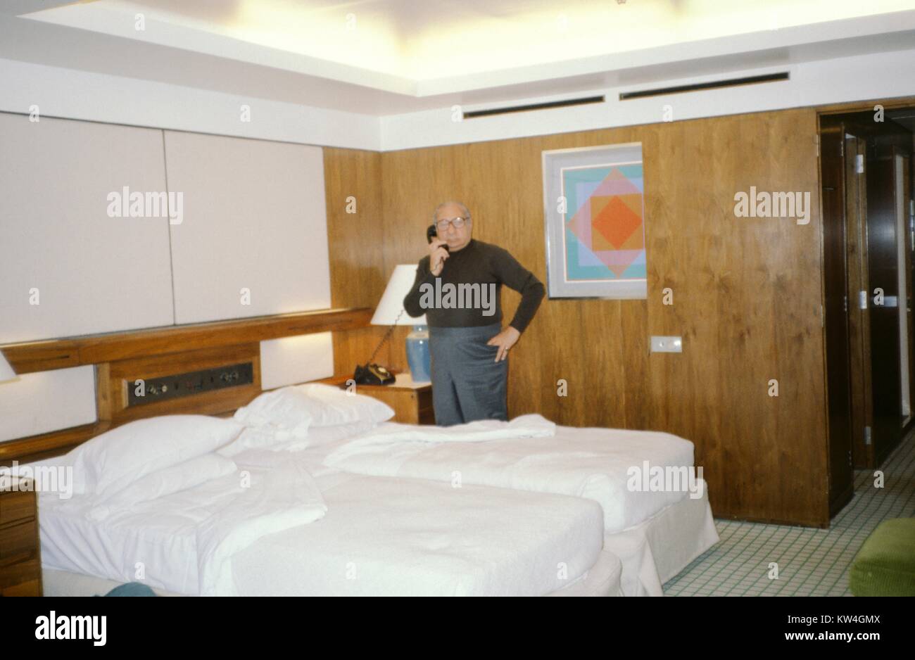 Male tourist stands and speaks on the phone in a stateroom aboard the Cunard Line's Queen Elizabeth 2 cruise ship, at sea, 1975. Stock Photo