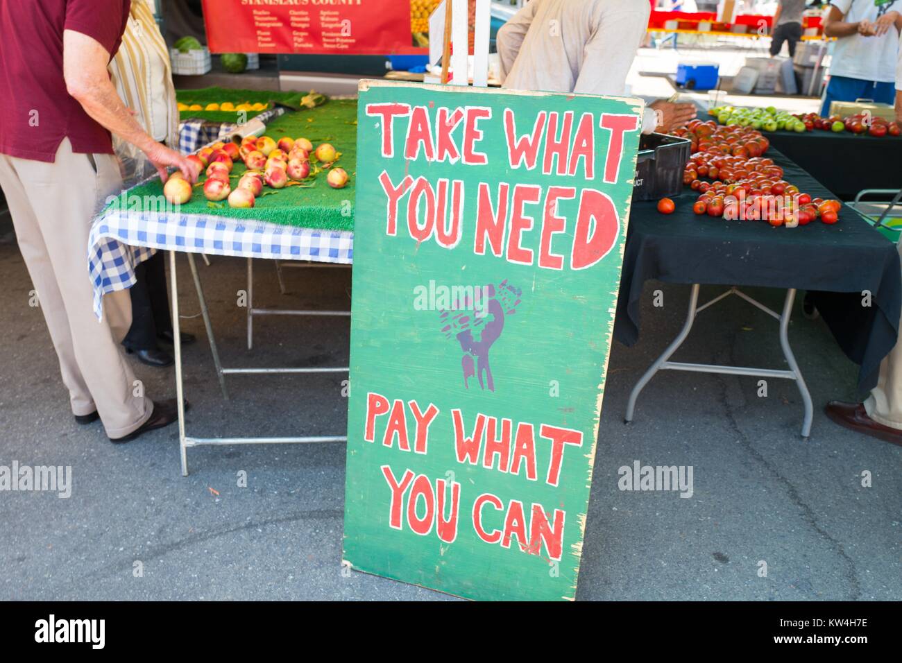 A a farmer's market in the San Francisco Bay Area town of Danville, California, a sign for a collective farm features an image of a fist holding a sheaf of wheat and urges visitors to 'Take what you need, pay what you can', August 13, 2016. Stock Photo