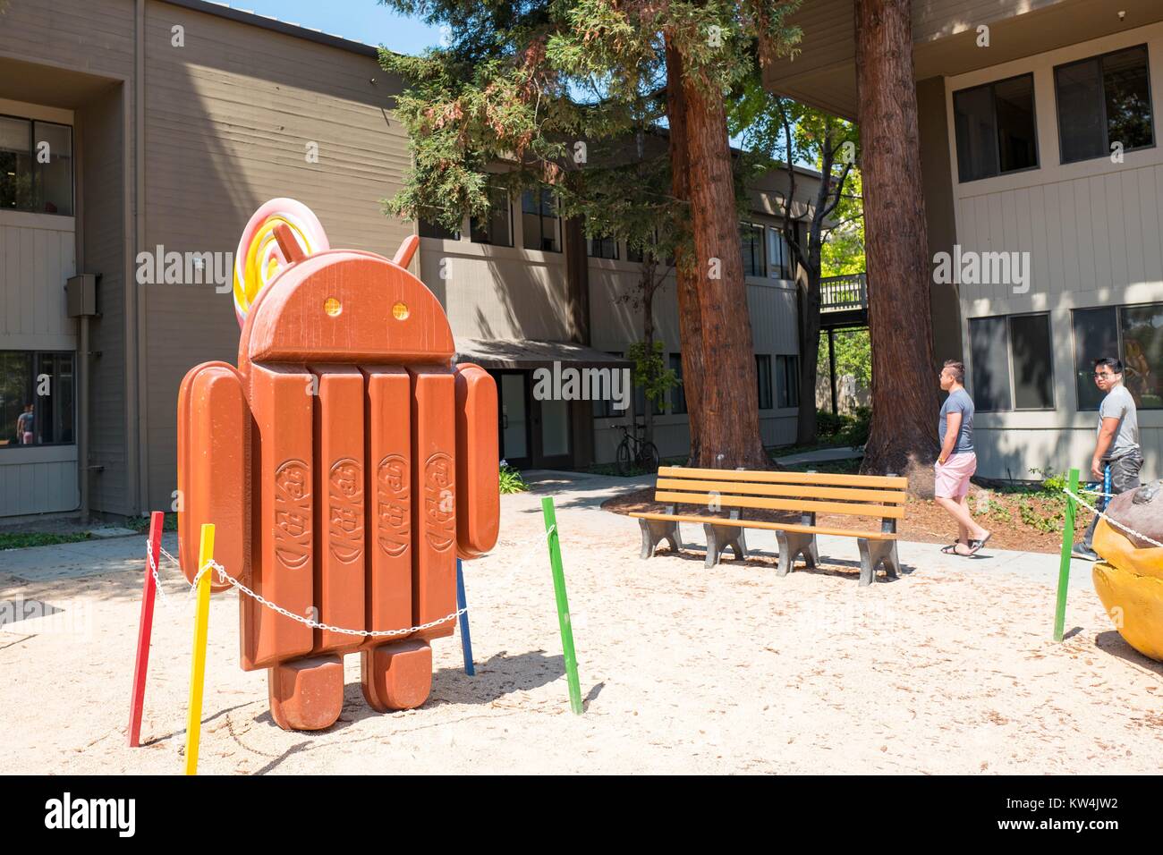 Two men walk near a sculpture representing Version 4.4 of the Android ...