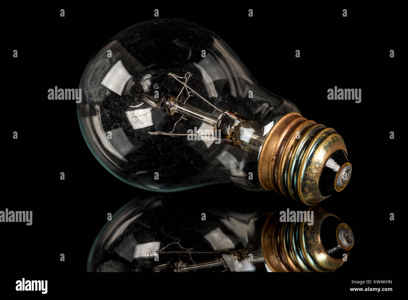 Incandescent light bulb on a highly reflective surface Stock Photo Alamy