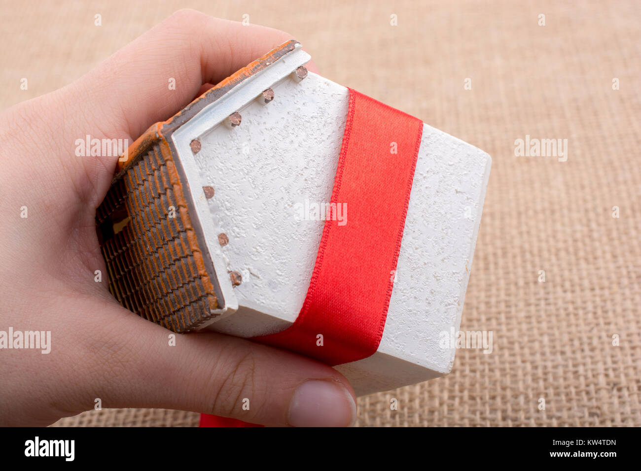 Little model house wrapped in red ribbon on a canvas Stock Photo - Alamy