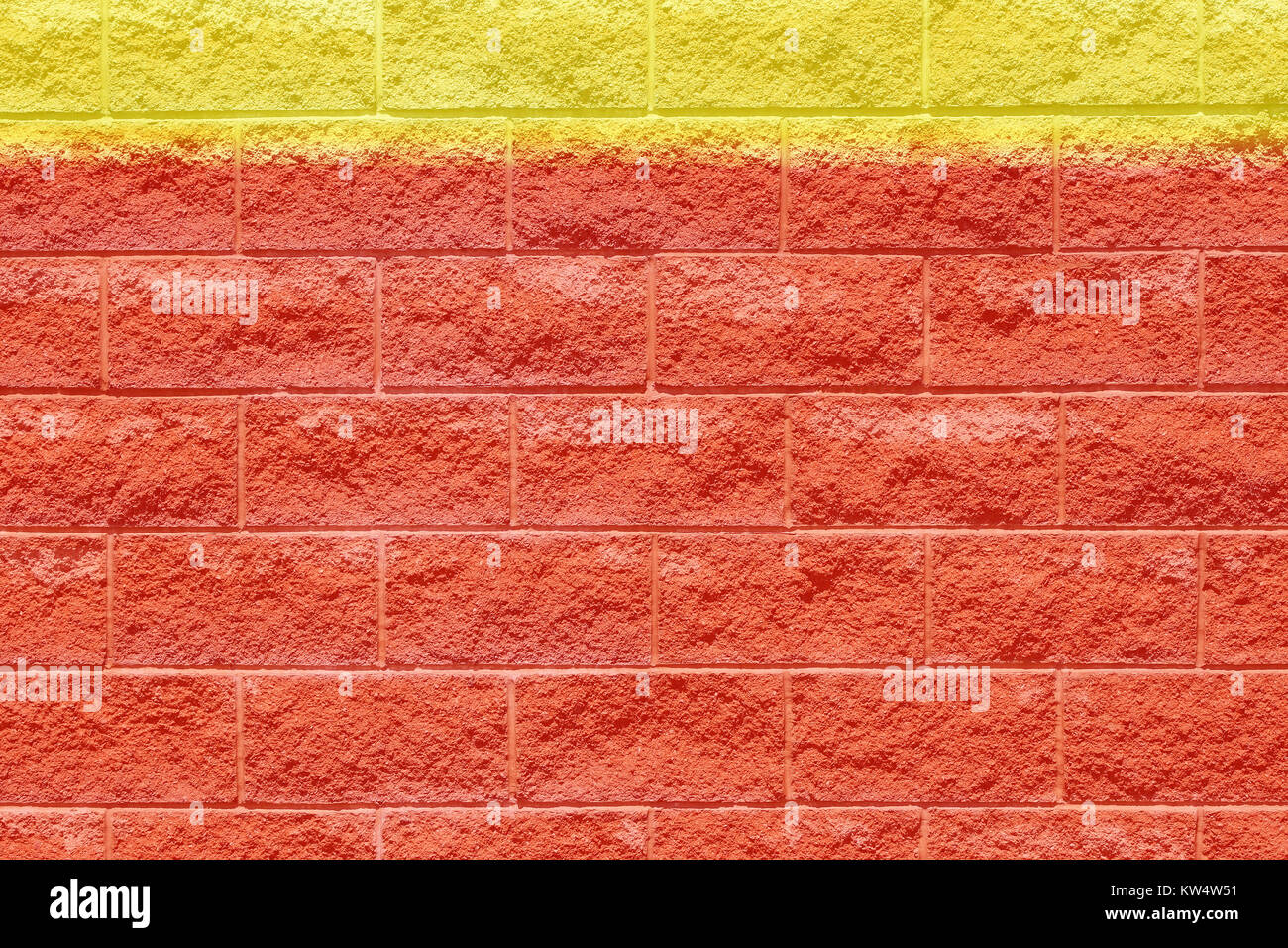 Red brick wall with abstract yellow strip of painted color along top Stock Photo