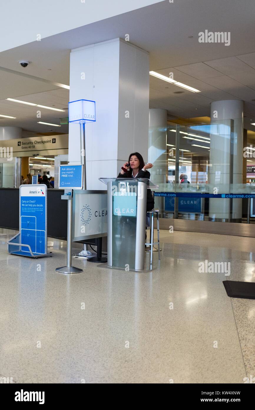 A woman sits at a kiosk and speaks on her cellphone while waiting for customers at the Clear security checkpoint at San Francisco International Airport, South San Francisco, California, September 24, 2016. Clear is a private company which offers expedited security screenings at several airports, including San Francisco International. Stock Photo