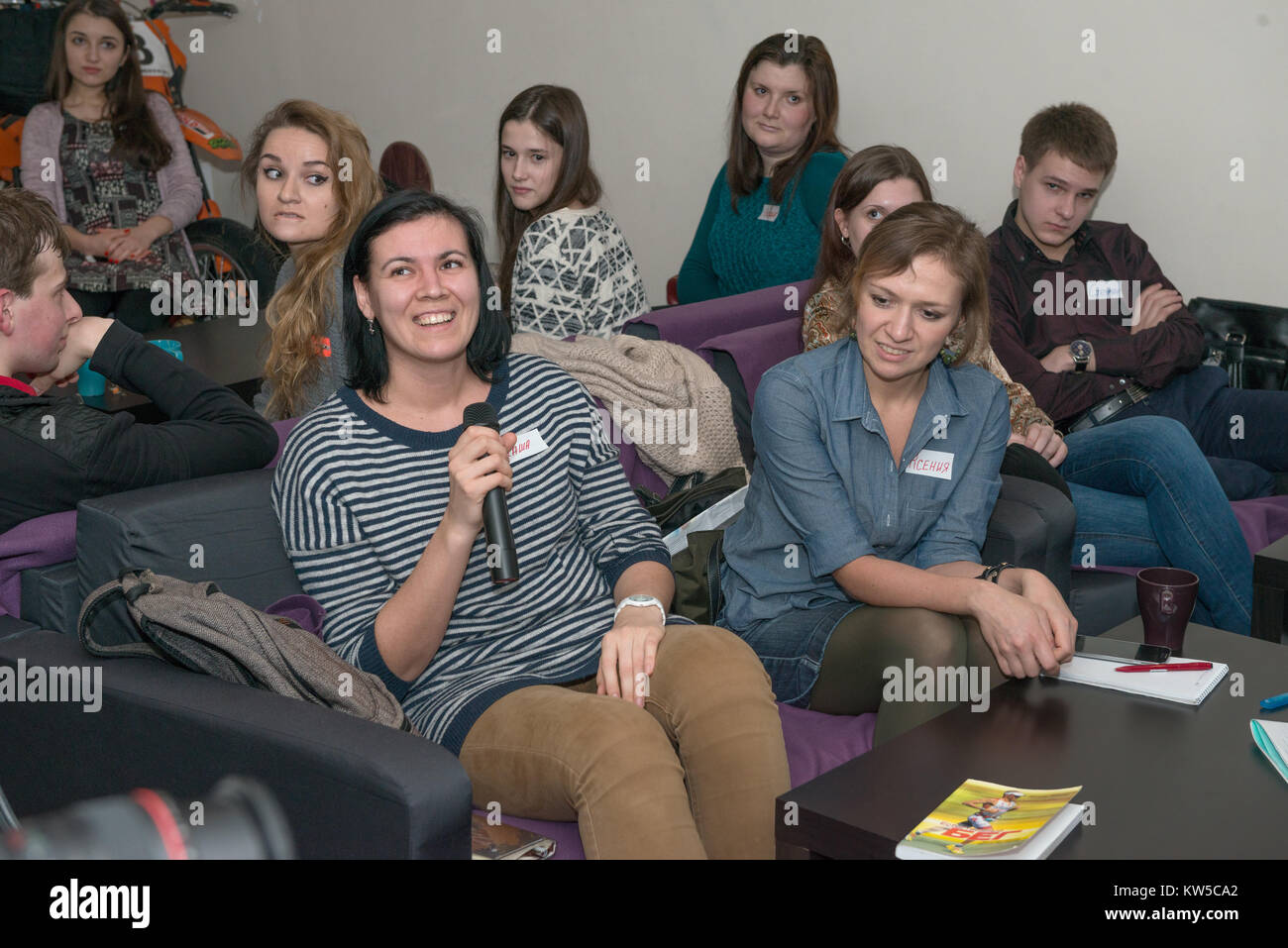 Group of young Russian people on are listening carefully one of talk partner at the public meeting on learning conversational English. Stock Photo