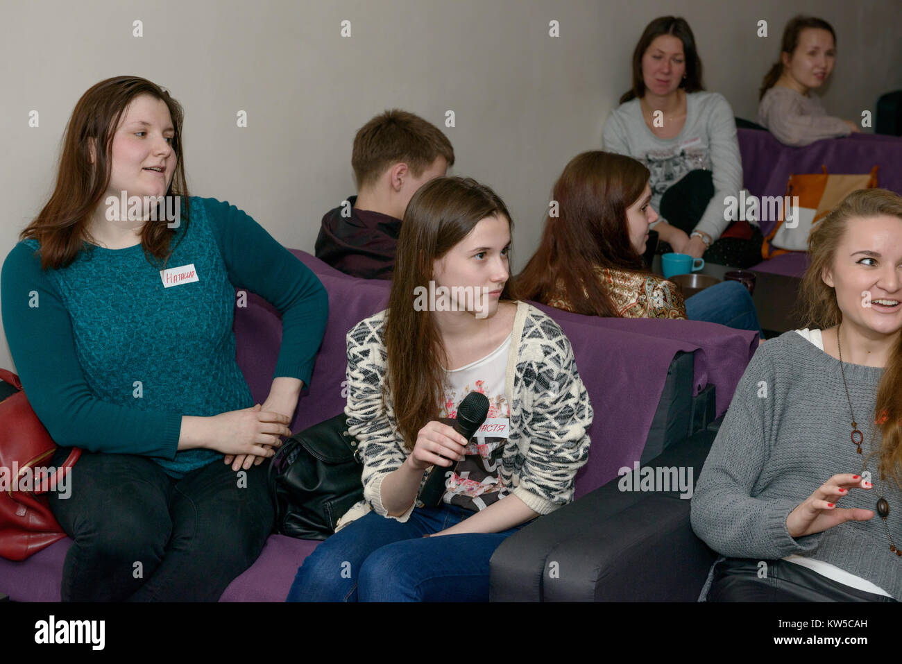 Group of young Russian people on are listening carefully one of talk partner at the public meeting on learning conversational English. Stock Photo