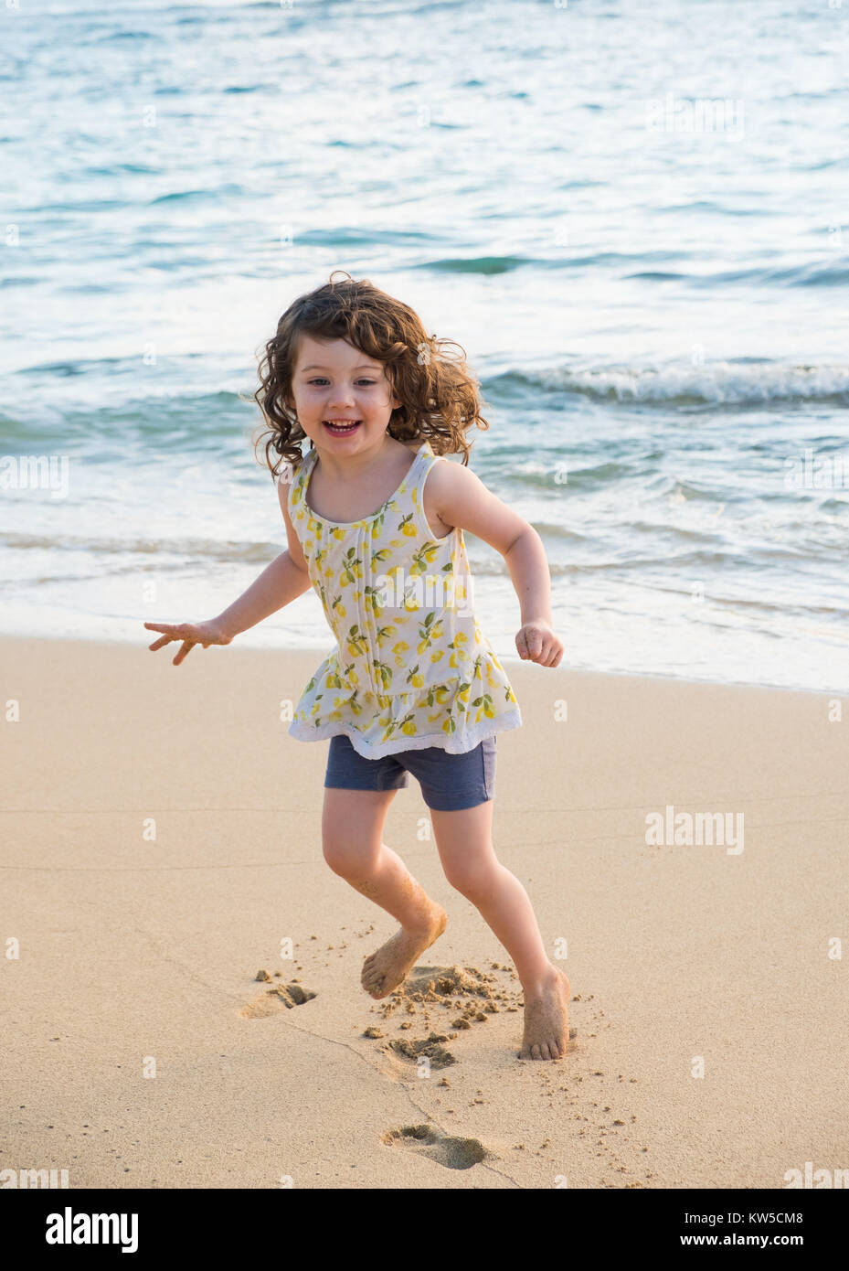 Three year old girl dancing on the beach in Oahu Hawaii while having ...