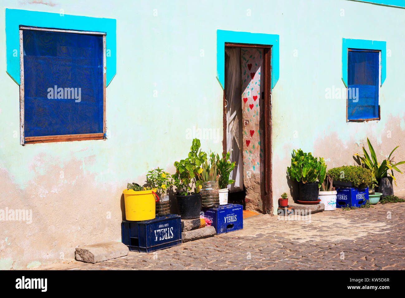 House in Palmeira, Cape Verde with small flowers and plants outside and decorative love hearts painted in the inside of the doorway. Salina Africa Stock Photo