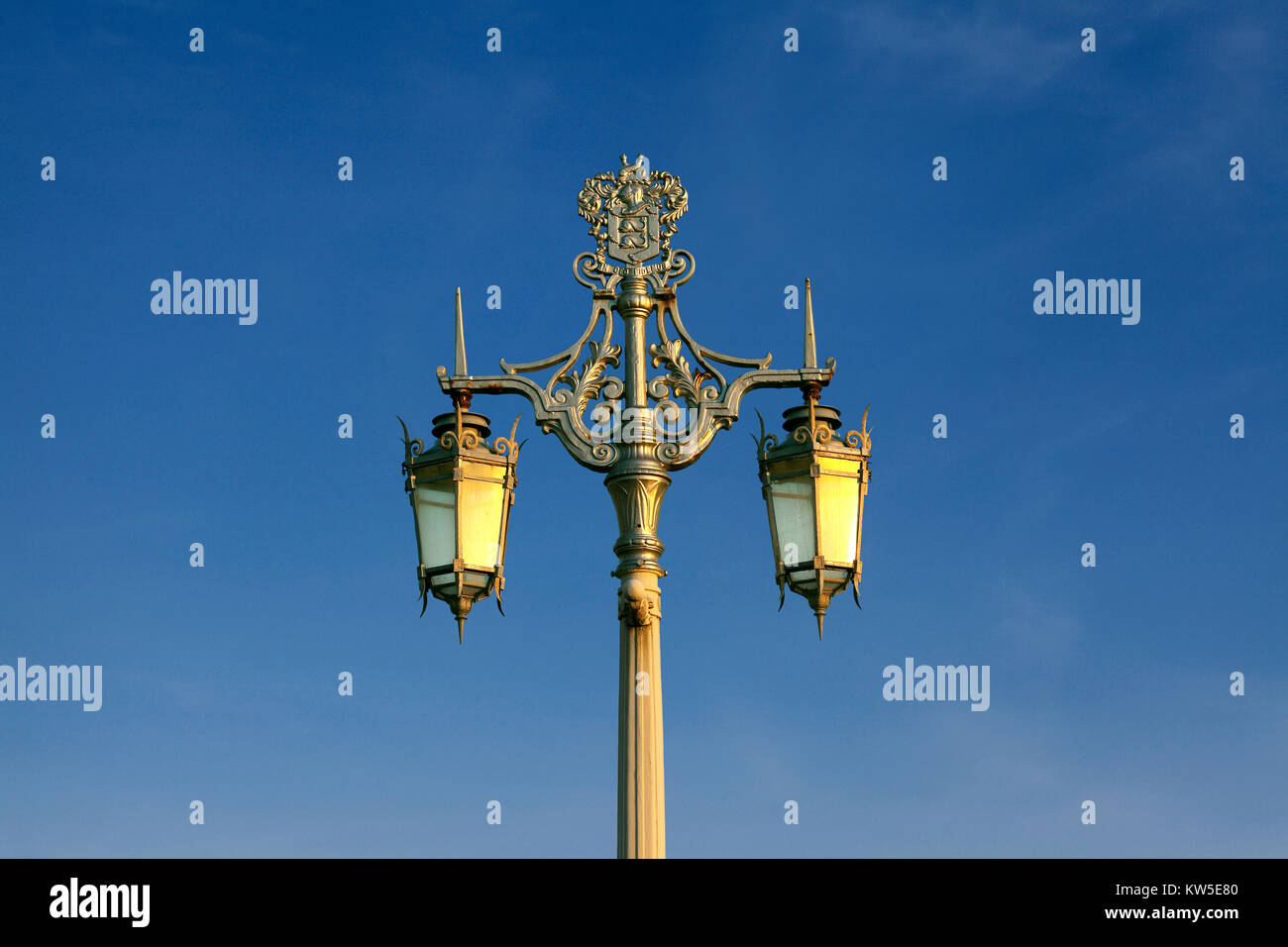 The evening sun catches an historic, ornate, cast iron lamp-standard on Madeira Drive, Brighton. One of 41 installed in 1893 along the seafront. Stock Photo