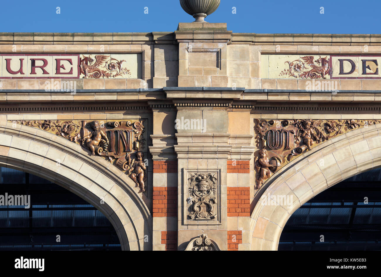Ornate 'In' and 'Out' lettering in spandrels on the arched frontage of the late-Victorian (1892) London Road railway station, Leicester. Stock Photo