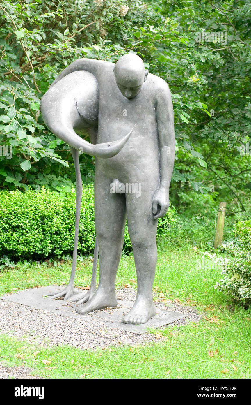 Sculpture of man standing embracing bird Stock Photo