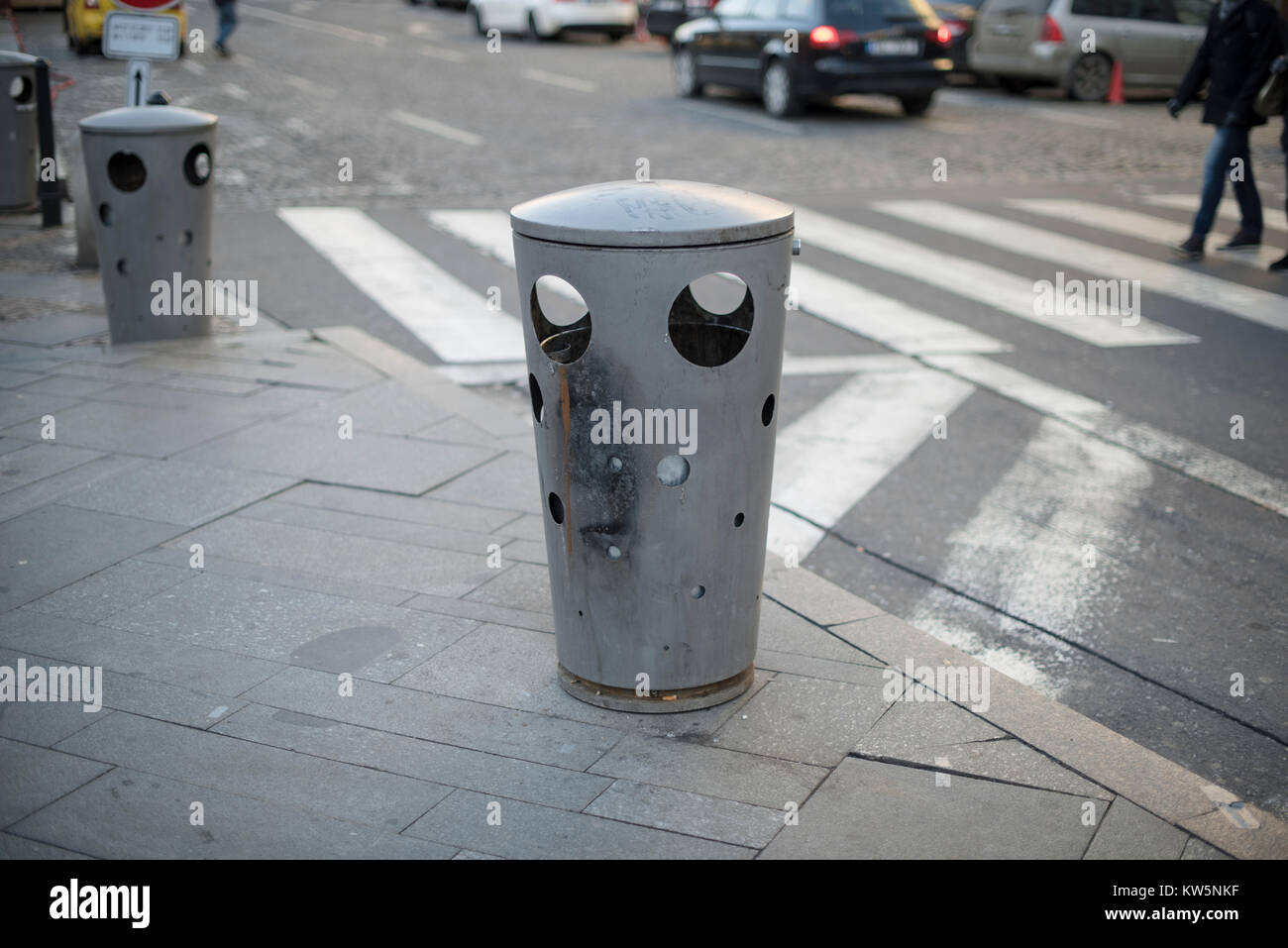 https://c8.alamy.com/comp/KW5NKF/a-metal-city-bin-showing-signs-of-burn-with-a-road-and-a-zebra-crossing-KW5NKF.jpg