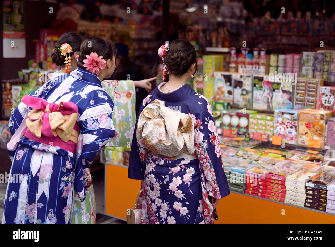 Japanese girls in bright Yukatas stopped by a souvenir store with traditional Kyoto treats and desserts on Matsubara dori street near Kiyomizu-dera. H Stock Photo