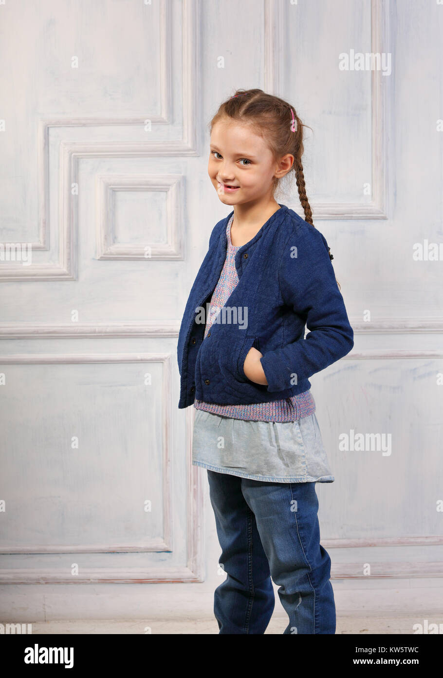Smiling happy cute kid girl in blue jeans jacket on studio blue
