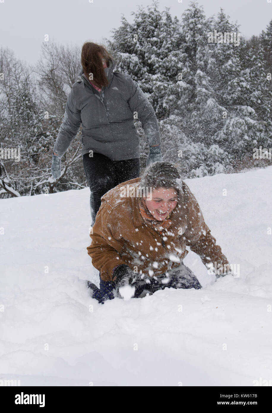 Sisters Eliza, 26, top, and Georgia Doolittle, 17 have a snow ball fight in Maine Stock Photo
