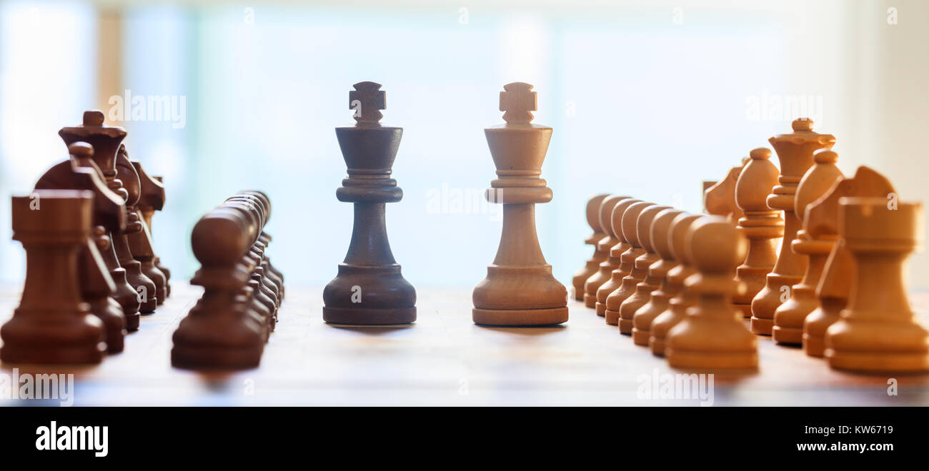 Chessboard blurred with chess pieces on it. Close up view with details, white backdrop. Stock Photo