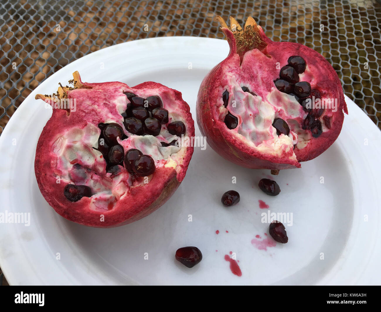 Opened pomegranate and seeds on white plate Stock Photo