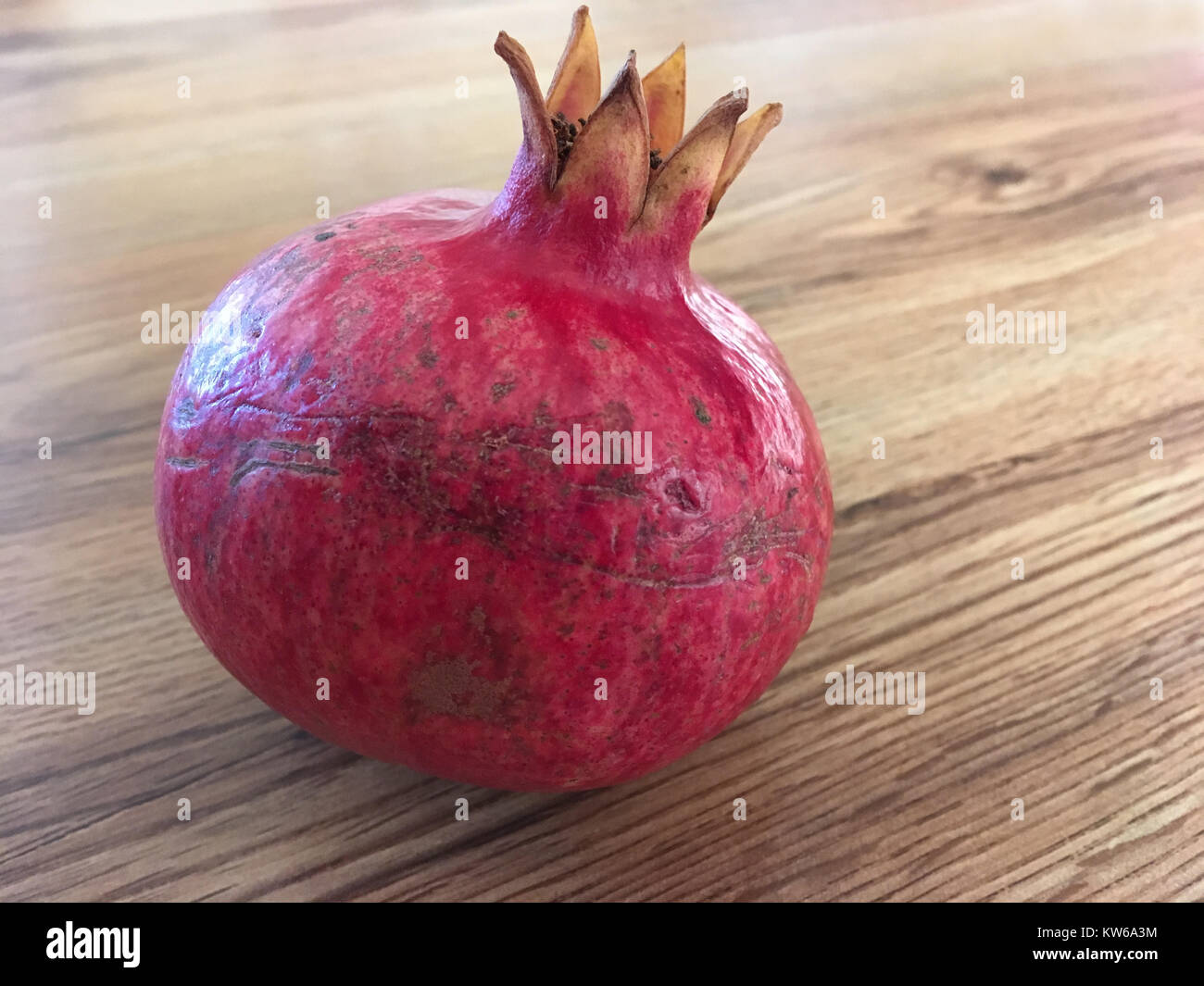 Pomegranate on wood grained table Stock Photo