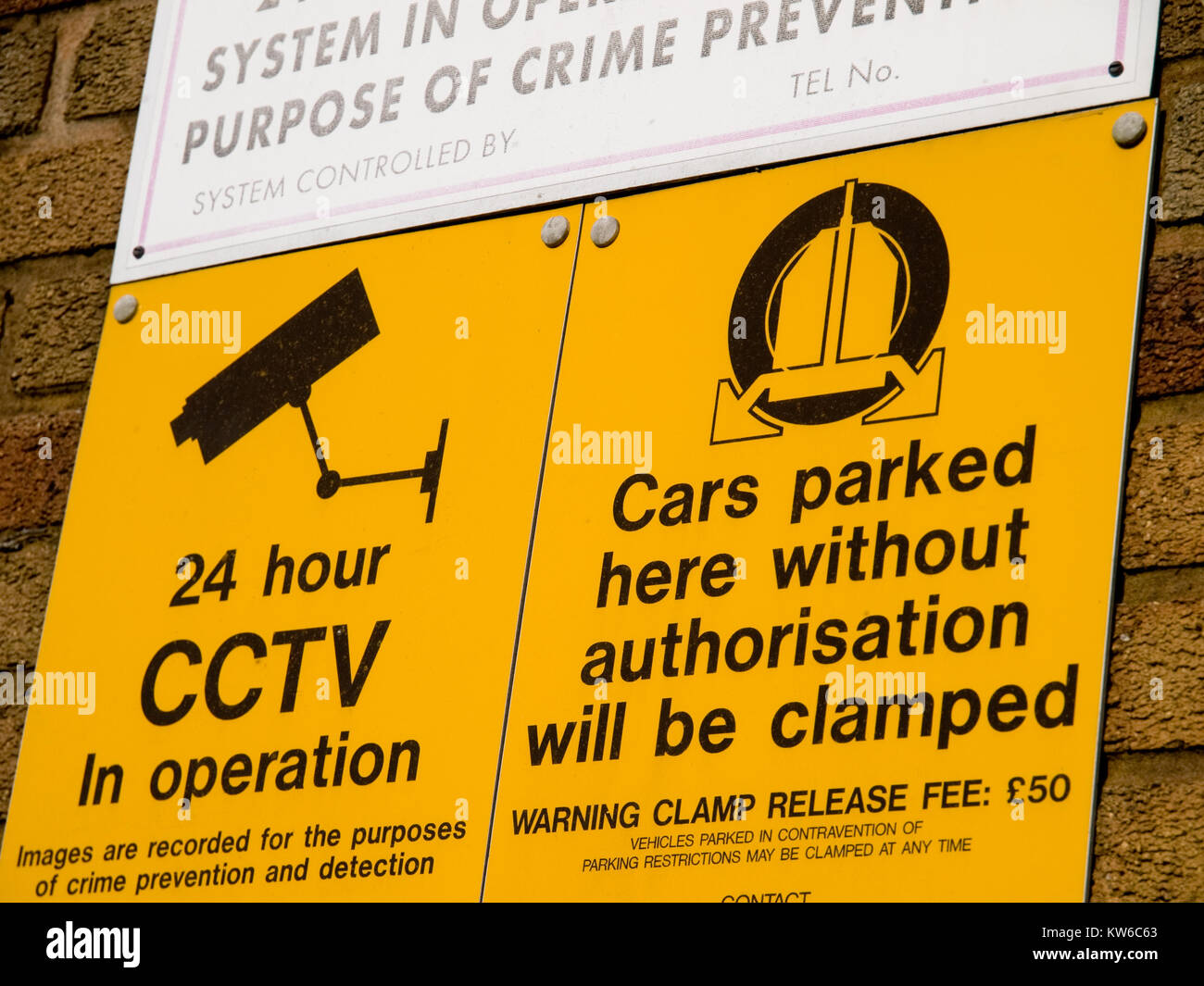 Security sign on a wall warning of clamping if parking is unauthorised Stock Photo