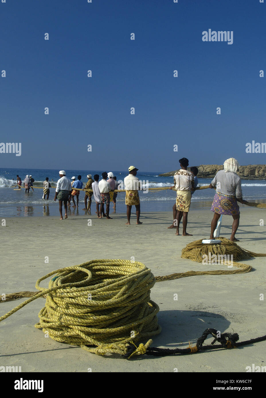 A line of fishermen in Kovalam, Kerala, India pulling on a rope to