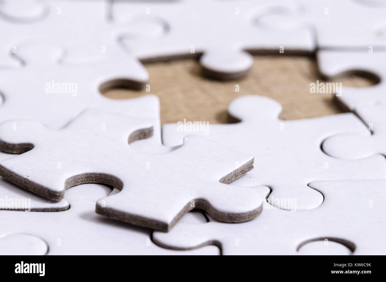 close up of a white jigsaw/puzzle whit one gap, over wooden table  background, symbol of problem solving Stock Photo - Alamy